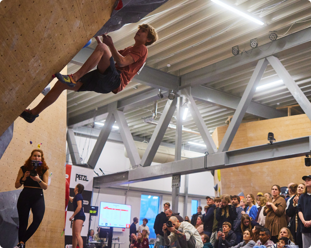 An athlete competing in front of spectators at a climbing event